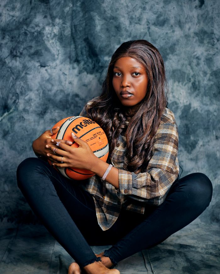 Young woman in plaid shirt holding basketball, studio setting.