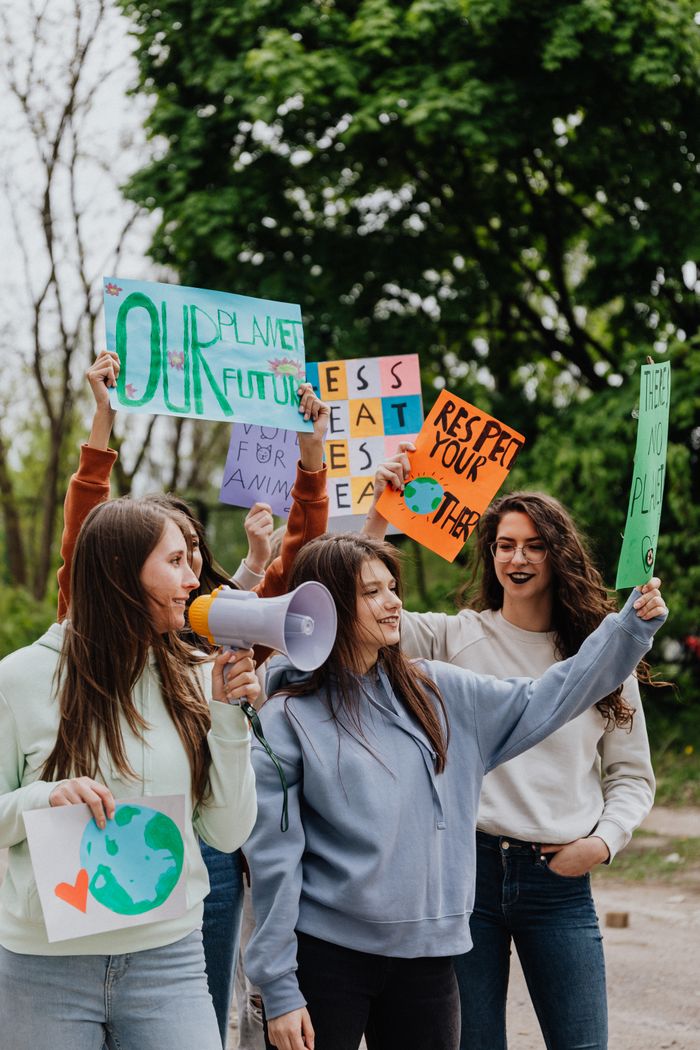 services-03 Group of young women holding protest placards for environmental activism outdoors.