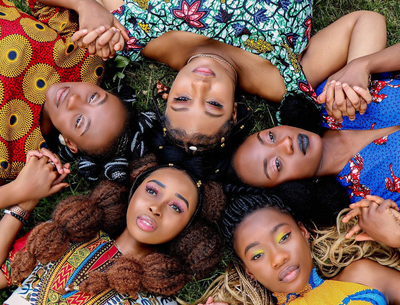 services-04 A group of diverse African women lying on grass holding hands, symbolizing unity.